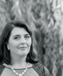 Black and white photo of Svitlana Kravchenko, who has light skin, shoulder-length dark hair, and is wearing a floral necklace.